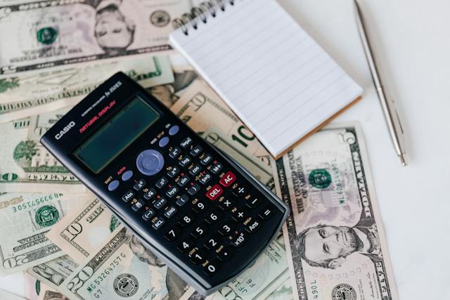 a calculator and notepad resting on top of cash